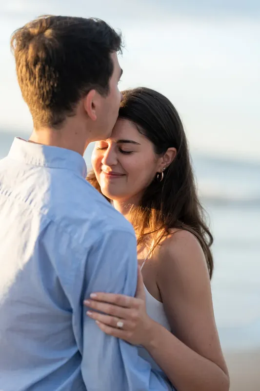 Sally rests her head against Pasha's chest as he holds her close on St. Augustine Beach during golden hour.