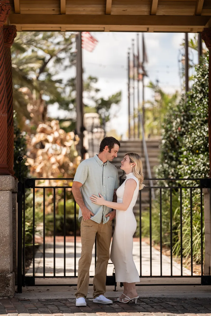 Samantha and Dillon stand in a doorway framed by ivy, with a historic church spire visible through the opening behind them.