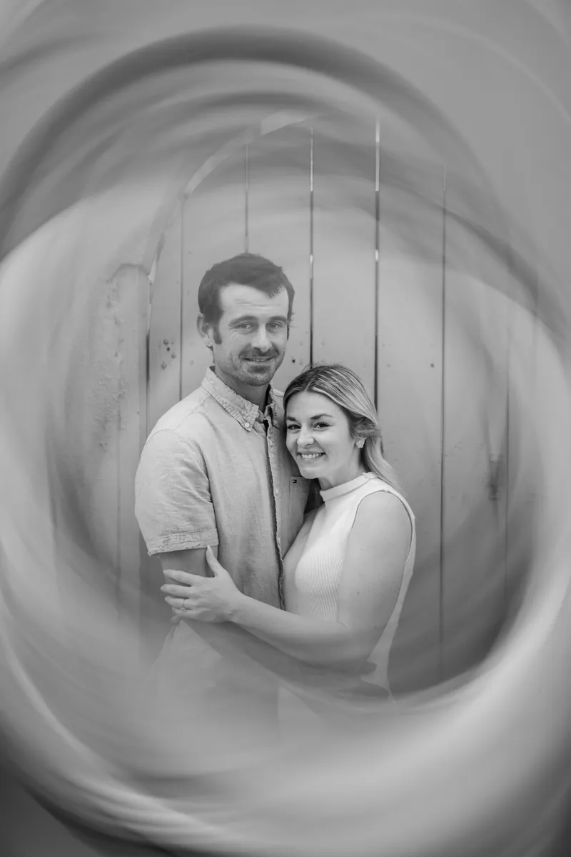 Dillon and Samantha stand together inside a circular concrete tunnel structure in black and white.