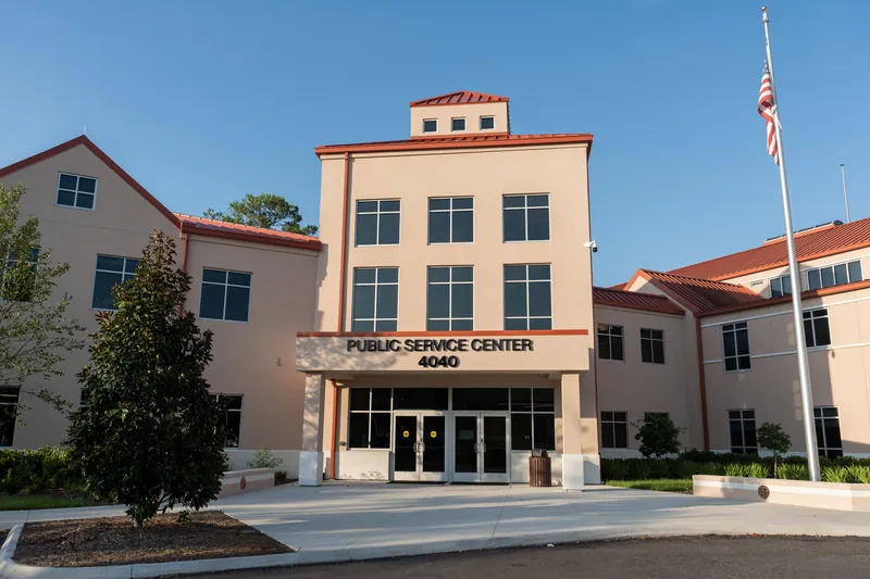 Peach-colored St. Johns County Courthouse with cupola and American flag under blue sky.