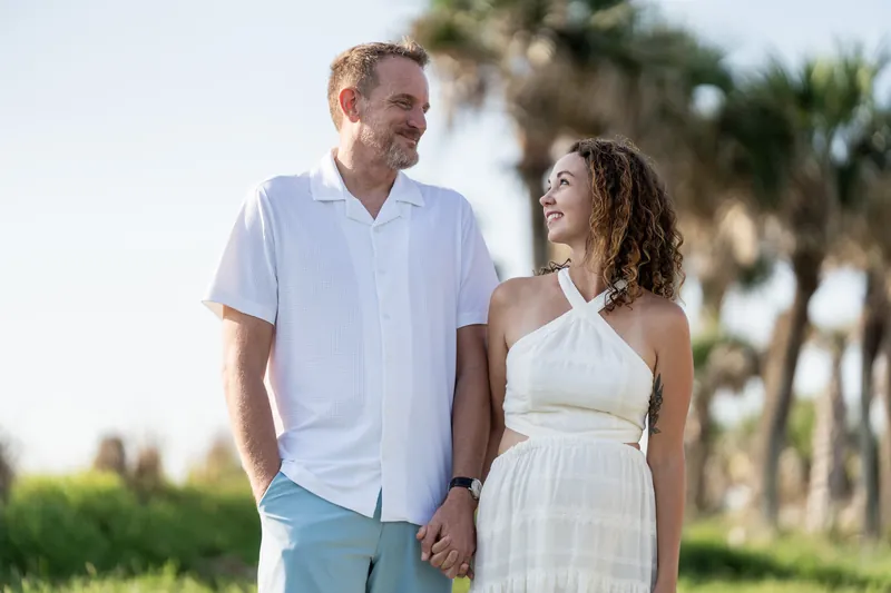 At Vilano Beach, Daniel and Samantha walk hand in hand with palmettos and open sky visible behind them.