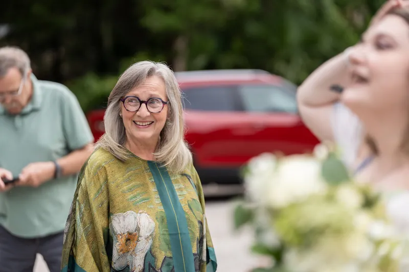 Family members gather and laugh together at Washington Oaks Gardens, with a red car visible in the background.