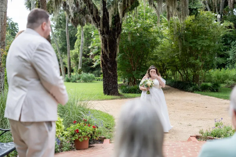 Matthew turns to face Samantha as she holds her bouquet during the outdoor ceremony with guests nearby.