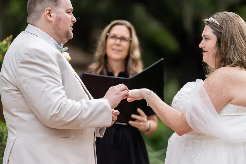 Matthew and Samantha exchange rings at Washington Oaks Gardens State Park as their officiant holds the ceremony book.