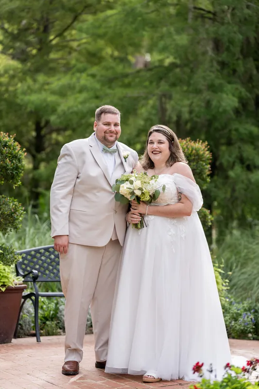 Samantha holds a white bouquet beside Matthew on a brick pathway at Washington Oaks Gardens State Park.