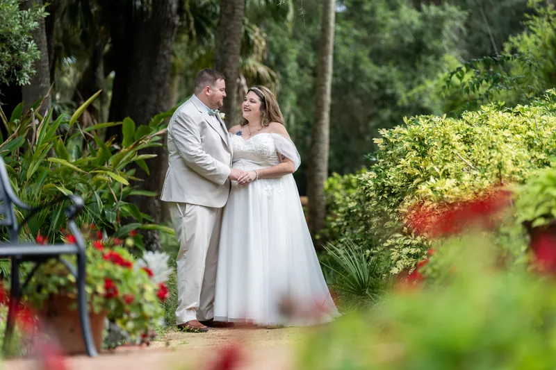 Samantha and Matthew embrace among blooming flowers and greenery at Washington Oaks Gardens State Park.