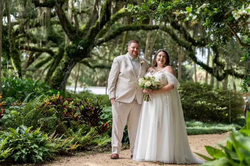 The couple pauses on a dirt path framed by lush greenery and moss-laden branches at Washington Oaks Gardens State Park.