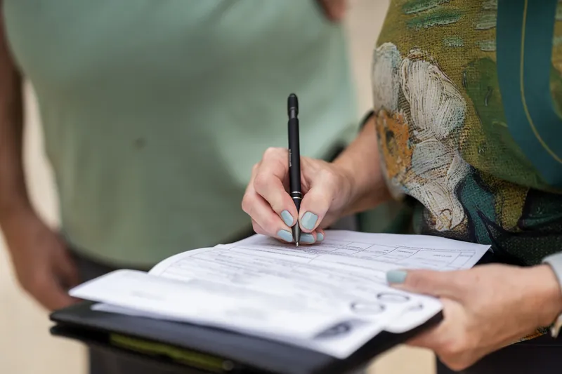 Someone in a sage-green shirt signs a document at Washington Oaks Gardens State Park.
