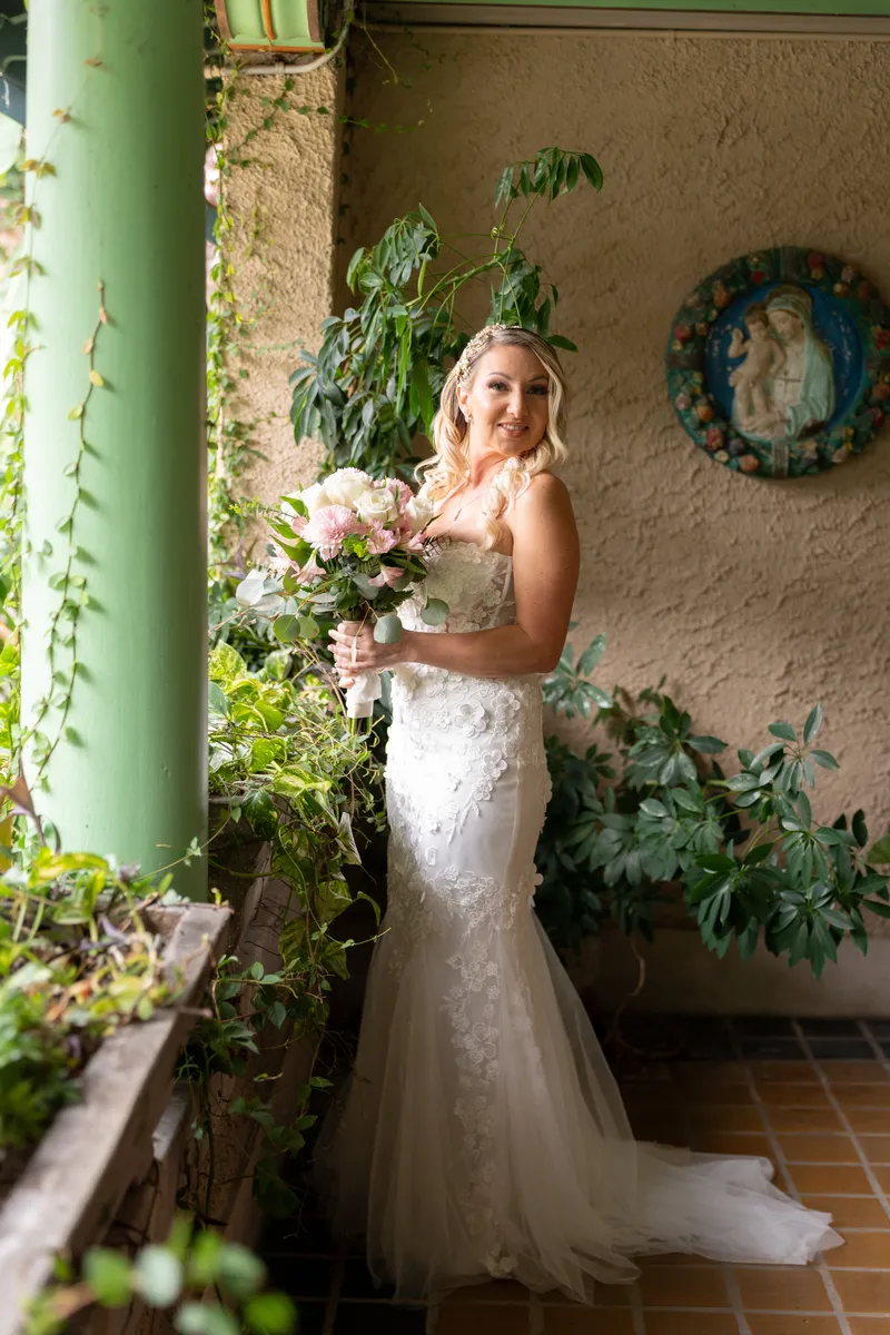Sara and Ian hold their bouquets on a riverfront terrace flanked by palms and ornamental urns at Club Continental.