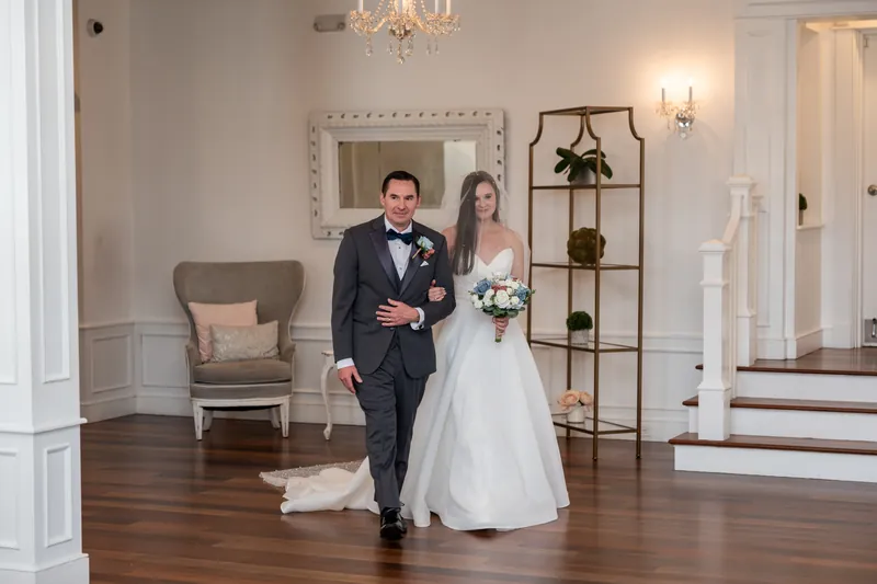 Nathan and Sarah walk hand-in-hand through The White Room's elegant foyer, Sarah in her flowing white gown and Nathan