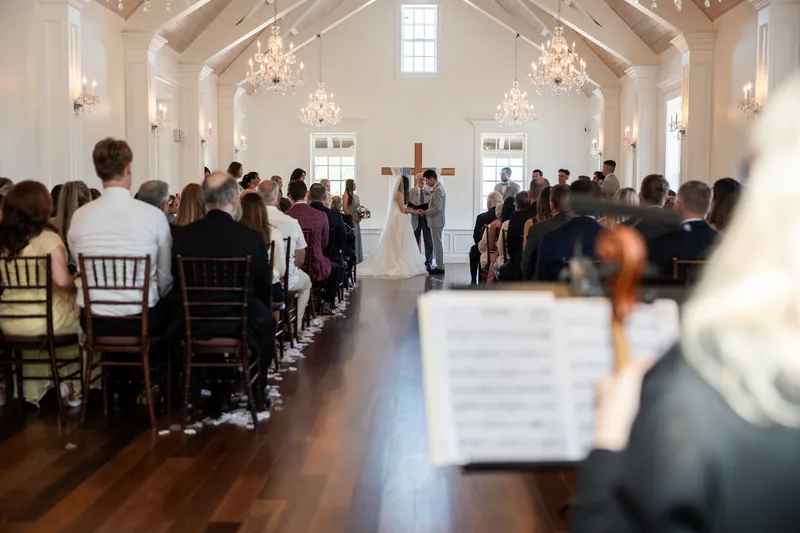 The couple stands together at the altar as the officiant leads the ceremony before rows of seated guests in The White Room's