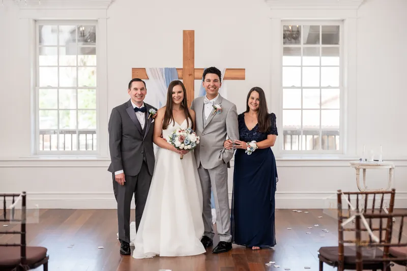 Nathan stands with Sarah, his brother in a dark suit, and a woman in black on either side of the couple at The White Room.