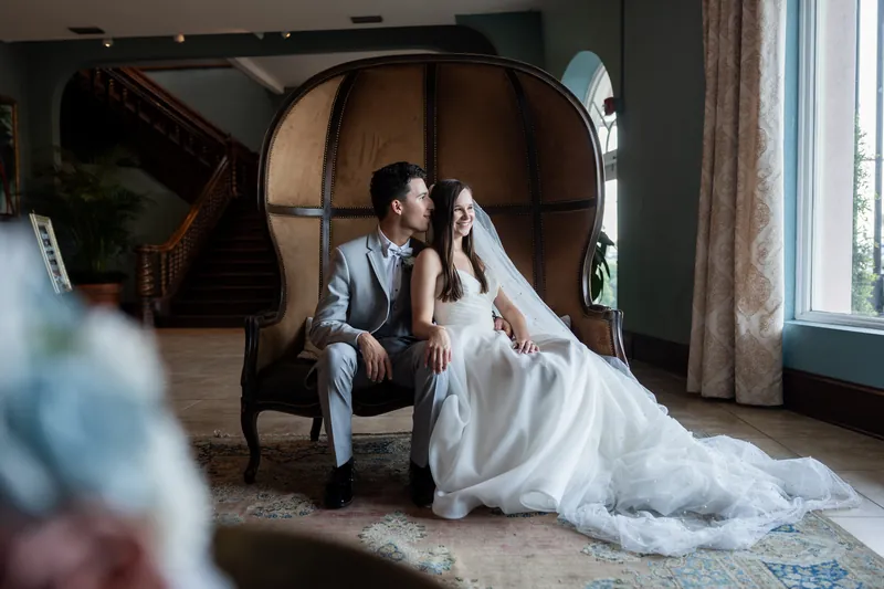Sarah laughs as Nathan admires her in profile, seated by a grand piano in the reception hall.