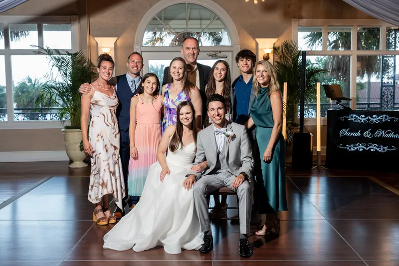 Nathan and Sarah pose with eight family members in the elegant venue's main hall, with the arched window and crystal