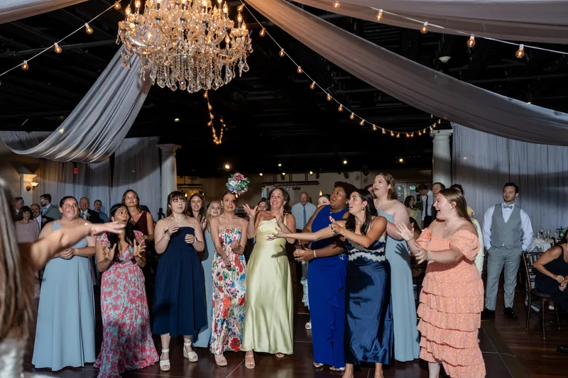 Wedding guests dance beneath draped fabric and a crystal chandelier at The White Room's reception.