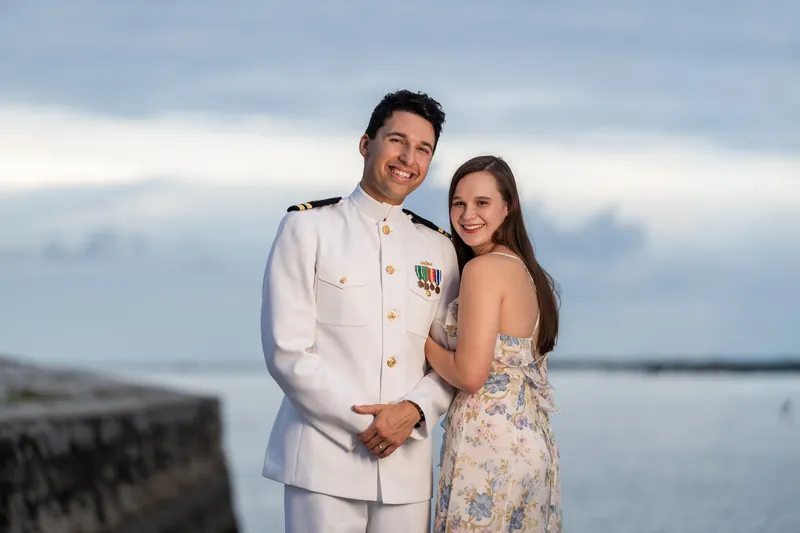 Sarah Katherine and Nathan embrace near the waterfront at Castillo de San Marcos under an overcast sky.
