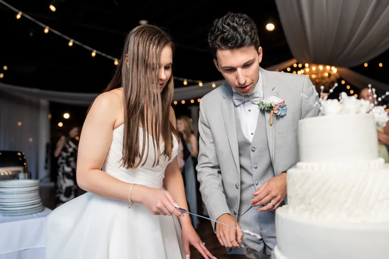 Sarah Katherine and Nathan cut their white tiered wedding cake together at the reception.
