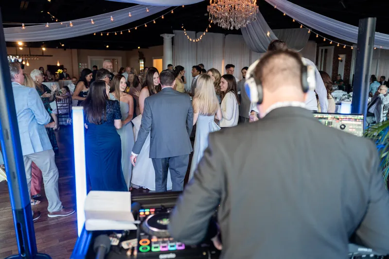 Guests fill The White Room's dance floor under string lighting as the DJ manages the music from a booth.