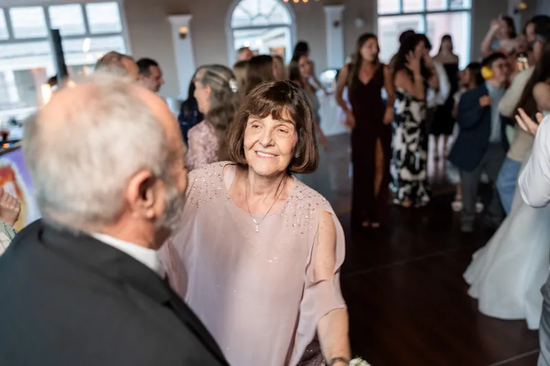 A woman in a pale pink blouse chats with an older man during the reception at The White Room.