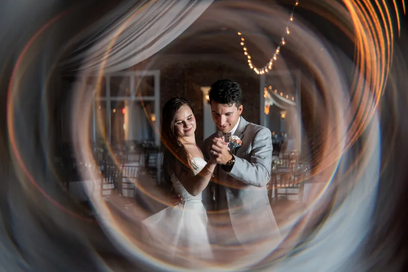 A couple dances cheek-to-cheek, seen through a swirled glass or lens effect that distorts the venue around them.