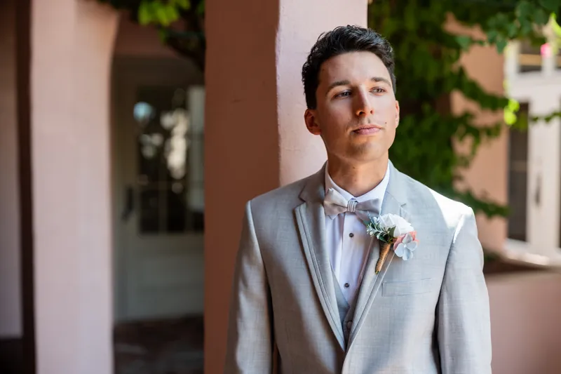 A man in a light gray suit and floral boutonniere gazes thoughtfully at The White Room before the ceremony.