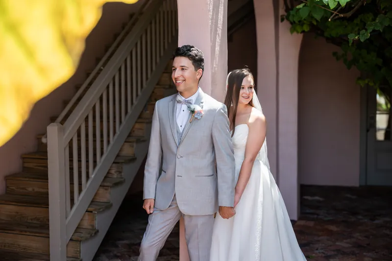 Two people walk hand-in-hand past wooden railings, bathed in warm golden sunlight.