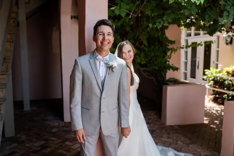 A couple moves through a terracotta-walled courtyard draped with climbing ivy and greenery.