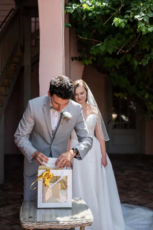 Sarah Katherine & Nathan open a gold-wrapped gift box together in the colonnade at The White Room, St. Augustine.