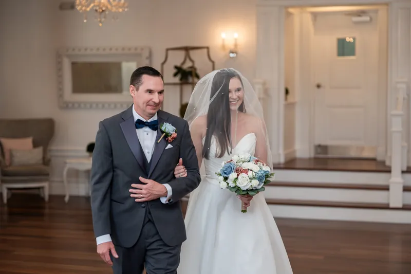 Sarah Katherine and Nathan walk down the aisle at The White Room, with guests seated on either side and flower petals scattered across the floor.