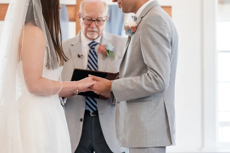 Two people exchange vows before an officiant holding a black book during their ceremony at The White Room, St. Augustine.