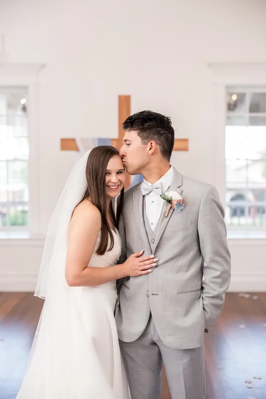 Two people in wedding attire face each other and smile at The White Room, St. Augustine.