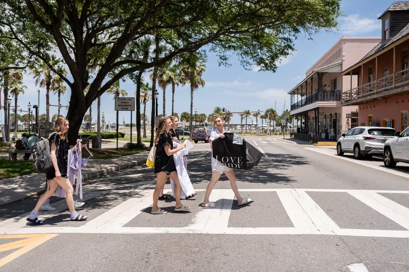 Wedding guests cross a downtown St. Augustine street beneath a large oak tree on a sunny day.