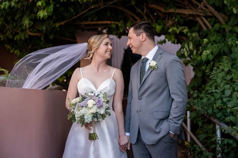 Sarah and Tim gaze at each other under draped fabric, Sarah's veil flowing behind them.