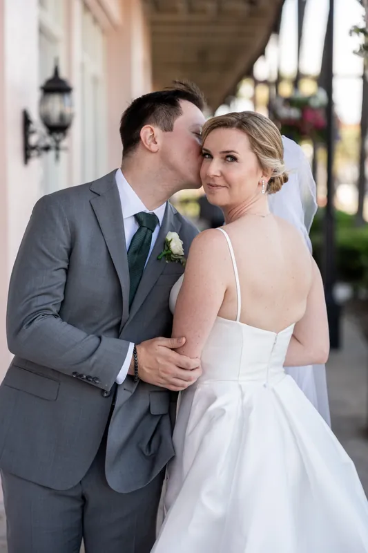 Tim and Sarah walk together on a columned outdoor corridor, both turning to look over their shoulders.