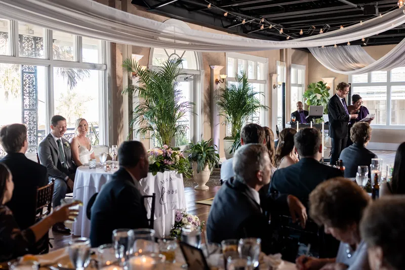 The couple dances while family and friends dine at tables beneath the draped ceiling and large windows.