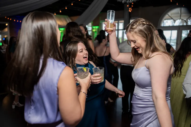 Wedding guests clink glasses and celebrate at The White Room, with three women in the foreground toasting during