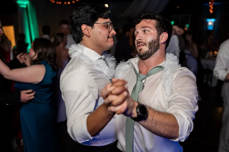 Two men in white shirts dance together on the lit dance floor at The White Room.