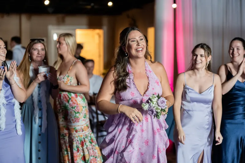 A woman in a purple skirt dances among several female guests in varied dresses at The White Room.
