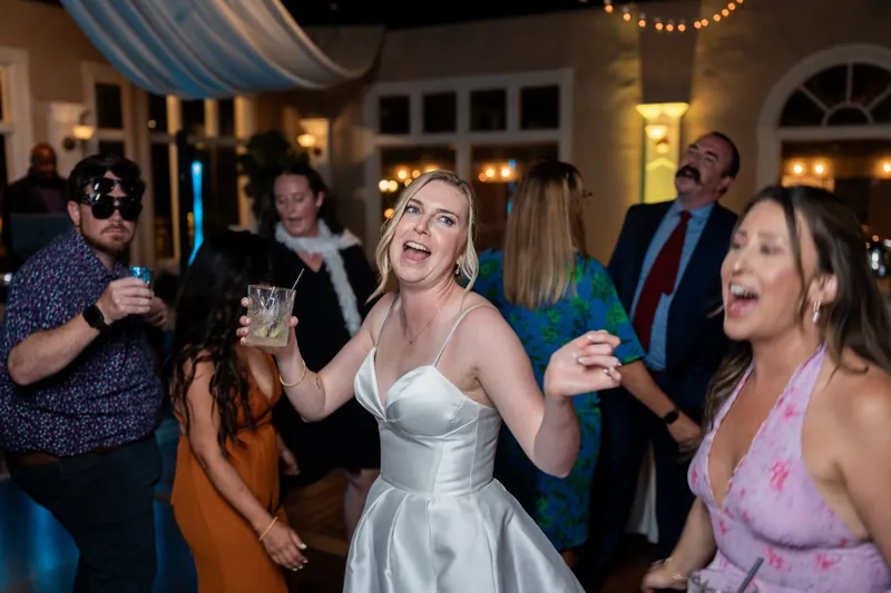 Sarah dances energetically among guests in a white strapless dress at The White Room's reception.