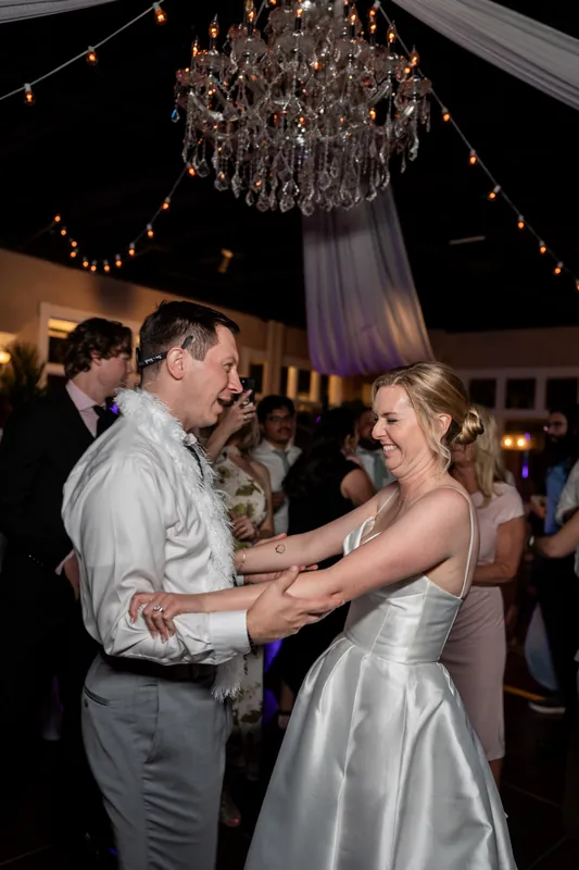 Tim and Sarah dance together under a crystal chandelier strung with golden lights.
