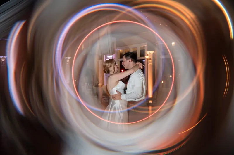 Sarah and Tim appear in concentric circles of warm light, dancing together during their first dance at The White Room.