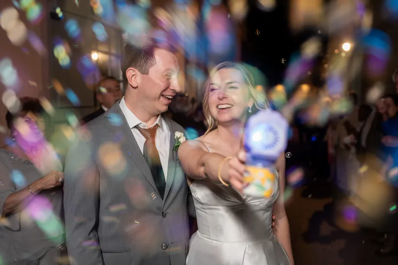 Tim and Sarah dance together amid colorful bokeh lights, both beaming as they move across the dance floor.