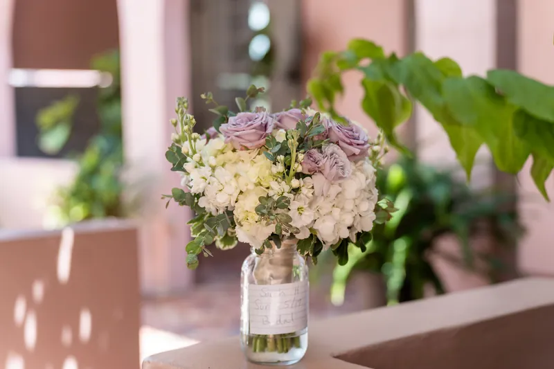 Pink and white hydrangeas with greenery fill a clear vase on a reception table.