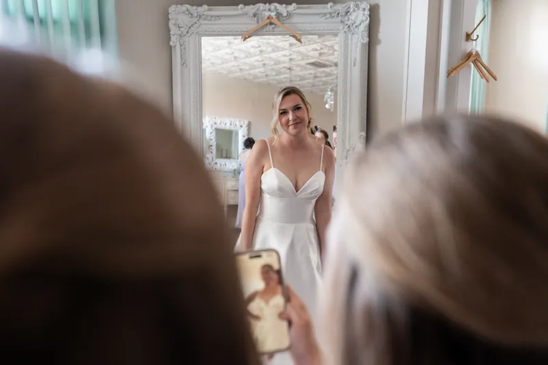 Sarah in a white sleeveless gown smiles at guests gathered before her at The White Room, St. Augustine.