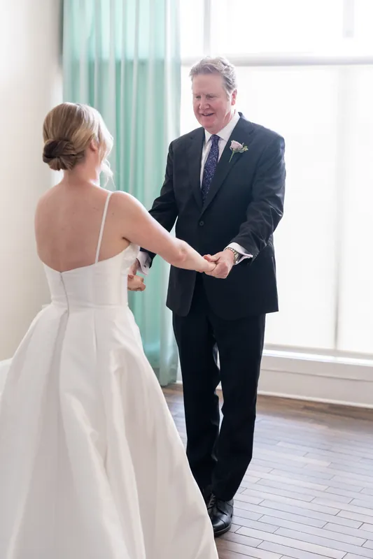 Tim holds Sarah's hand as they meet at The White Room, both smiling in anticipation during their first look.
