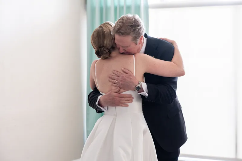Tim embraces Sarah from behind at The White Room, his eyes closed as she reaches back to hold him.