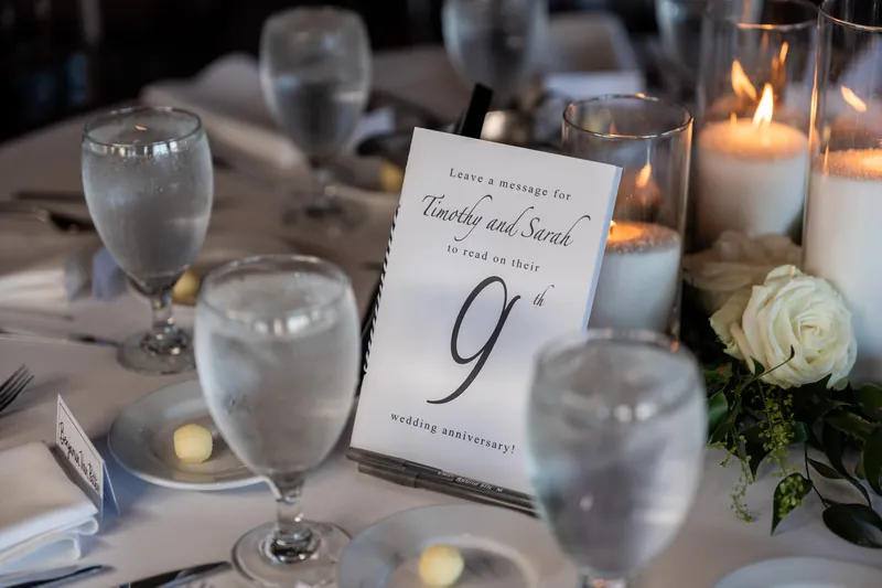 Table number 9 sits among water glasses, candles, and a white rose at The White Room.