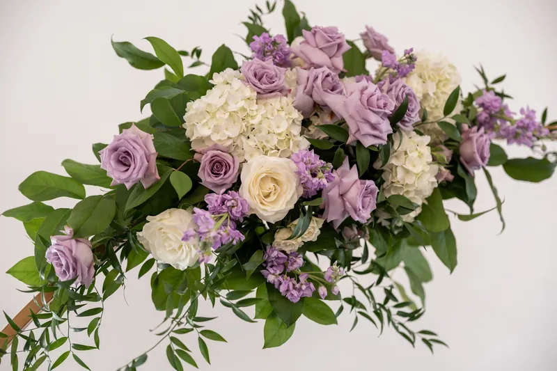 Purple and cream roses with greenery create a lush wedding arrangement at Villa Blanca.
