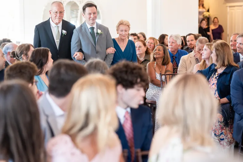 Guests gather indoors as the ceremony unfolds at Villa Blanca, with families watching intently.