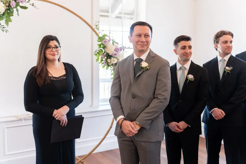 Tim stands at the altar with groomsmen as a woman waits to his left at Villa Blanca.